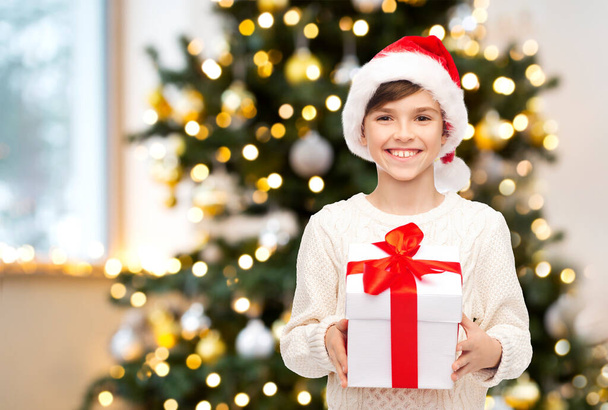 smiling boy in santa hat with christmas gift - Fotografie, Obrázek