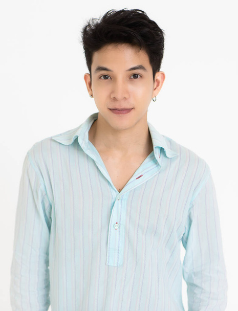 Joven y guapo adolescente negro cabello asiático hombre usando pendientes sobre fondo blanco. - Foto, imagen
