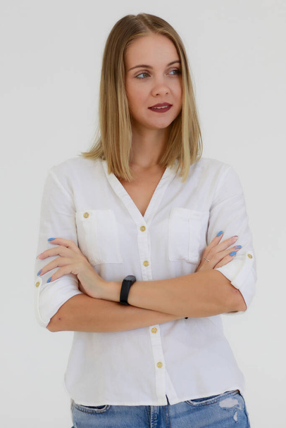 Портрет однієї кавказької дорослої жінки з довгим бронзовим волоссям, що стоїть, посміхається і дивиться на камеру з самовпевненістю. Жінка носить білу сорочку і джинсовий знімає білий фон в студії
. - Фото, зображення