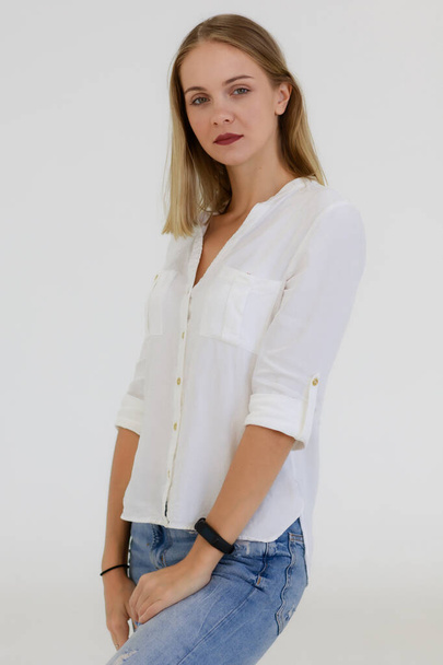 Portrait of One caucasian adult woman with long bronze hair standing, smiling and looking at a camera with self-confident. A woman wears a white shirt and jean shoot white background in a Studio. - Foto, immagini