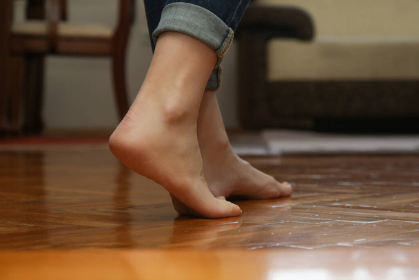 Floor heating. Barefoot woman walking on wooden flooring in modern house. Domestic underfloor heating concept. - Foto, Imagen