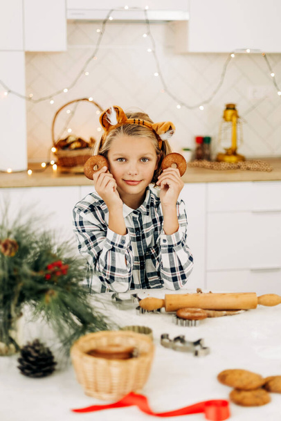 Πορτρέτο ενός χαρούμενου κοριτσιού που κρατάει ένα χριστουγεννιάτικο διακοσμητικό μπισκότο στο χέρι της. Προετοιμασία για τις γιορτές, Χριστουγεννιάτικο πνεύμα, Χριστουγεννιάτικα κεράσματα - Φωτογραφία, εικόνα