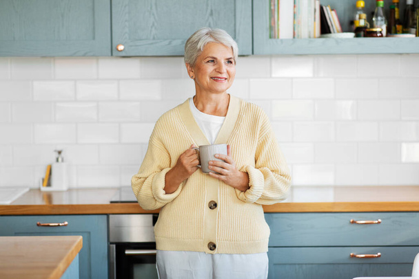 happy woman with cup of coffee on kitchen at home - Photo, image