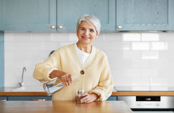 happy woman with jug of water on kitchen at home - Fotografie, Obrázek