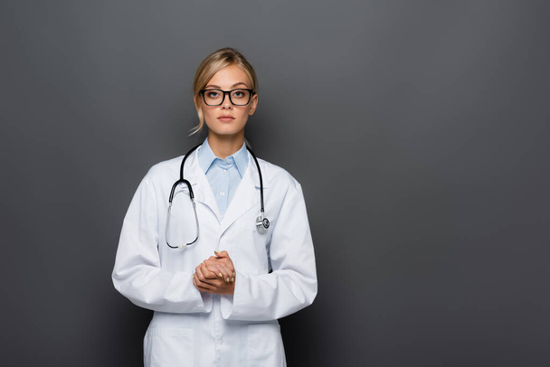 Blonde doctor in eyeglasses looking at camera isolated on grey  - Foto, imagen