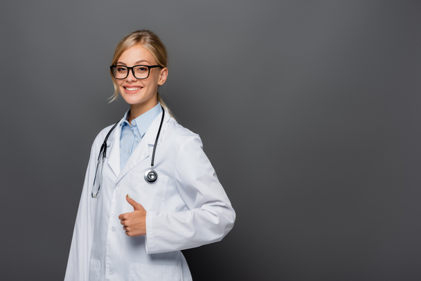 Positiver Arzt in Brille zeigt Geste isoliert auf grau  - Foto, Bild