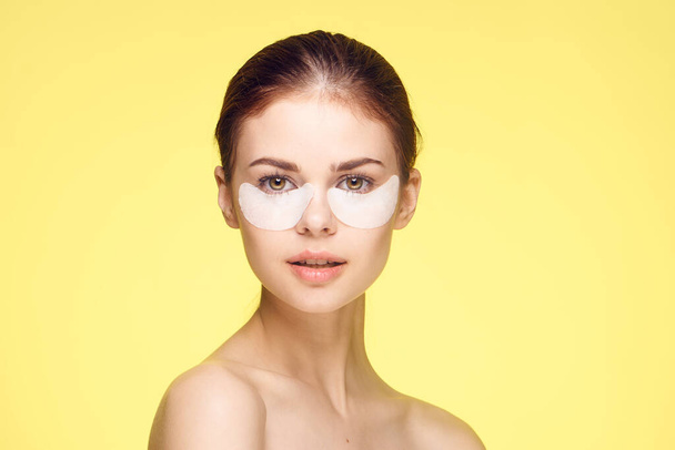 woman with bare shoulders and punchy rejuvenation skin care yellow background - Valokuva, kuva