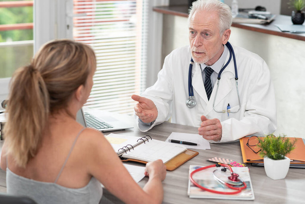 Senior doctor discussing with female patient in medical office - Photo, Image