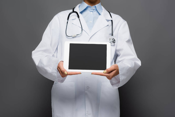 Καλλιεργημένη άποψη του γιατρού που δείχνει ψηφιακό δισκίο με λευκή οθόνη απομονωμένη σε γκρι  - Φωτογραφία, εικόνα
