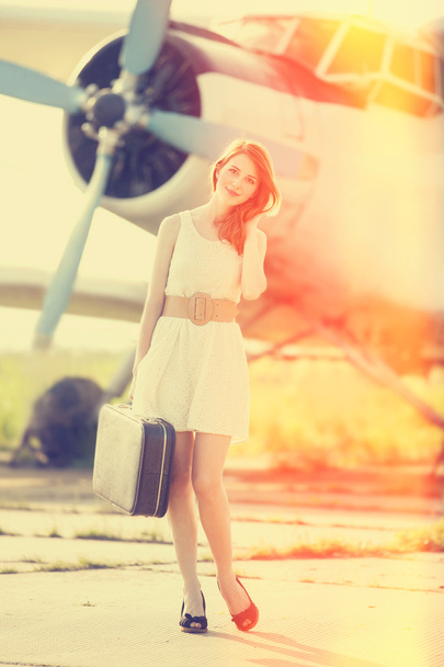 Lonely girl with suitcase at near airplane.  - Foto, afbeelding