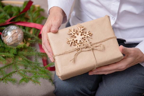 старі жіночі руки з різдвяним подарунком у ремісничому папері з ялинковою гілкою, сніжинкою
 - Фото, зображення