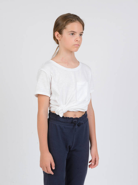 δείγματα μοντέλο, μέση υψηλό πορτρέτο, λευκό κορίτσι έφηβος σε σκούρο παντελόνι και ένα λευκό πουκάμισο σε λευκό φόντο, - Φωτογραφία, εικόνα