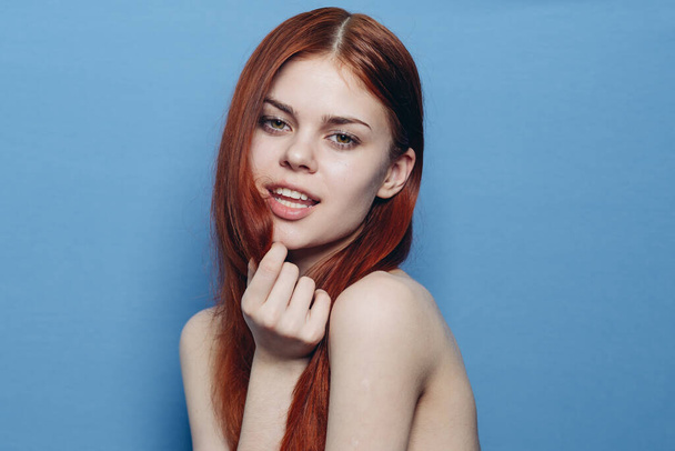 attractive woman with bare shoulders red hair close-up blue background - Foto, Imagem