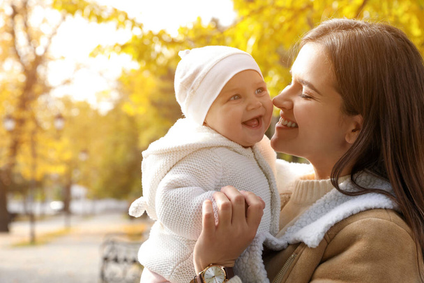Happy mother with her baby daughter in park on autumn day, space for text - Foto, imagen