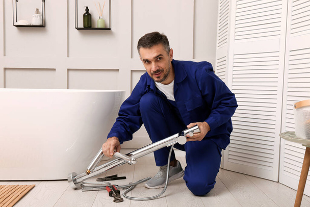 Professional plumber installing water tap in bathroom - Foto, afbeelding