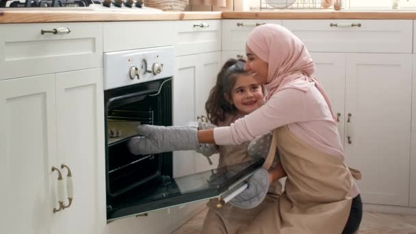Madre musulmana e hija tomando galletas del horno en la cocina - Metraje, vídeo