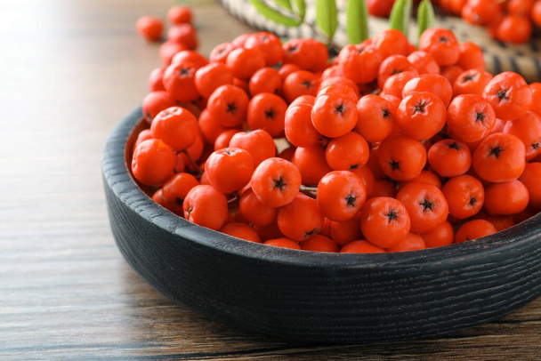 Plate with fresh ripe rowan berries on wooden table, closeup - Foto, afbeelding