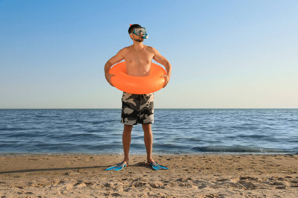 Man with flippers, inflatable ring and goggles on sea beach - Фото, зображення