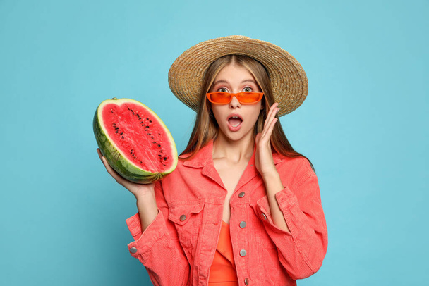 Beautiful girl with half of watermelon on light blue background - Zdjęcie, obraz