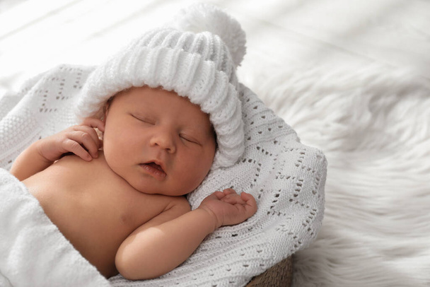 Cute newborn baby in warm hat sleeping on knitted blanket - 写真・画像