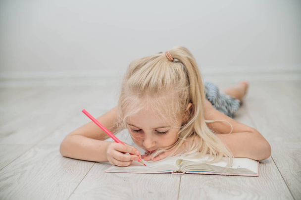 Мила дівчина малює кольоровими олівцями. Концепція домашнього навчання та освіти
. - Фото, зображення