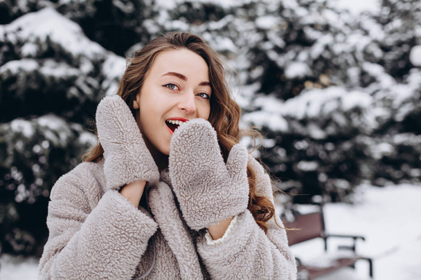 Portrait of surprised girl covers her mouth with hands wearing mittens and laughs - Foto, Imagen