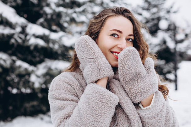 Close up portrait of surprised girl covers her mouth with hands wearing mittens and laughs - Fotoğraf, Görsel