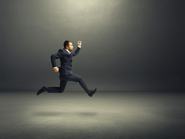 man in suit running fast in the dark room - Foto, imagen