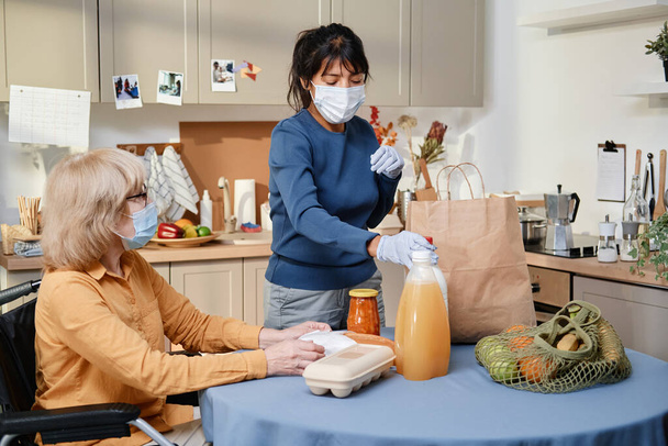 Dobrovolník doručuje jídlo starší ženě během pandemie - Fotografie, Obrázek