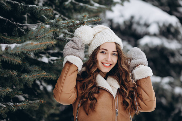 Крупный план портрета улыбающейся девушки в зимнем парке в ярких джинсах и рукавицах - Фото, изображение