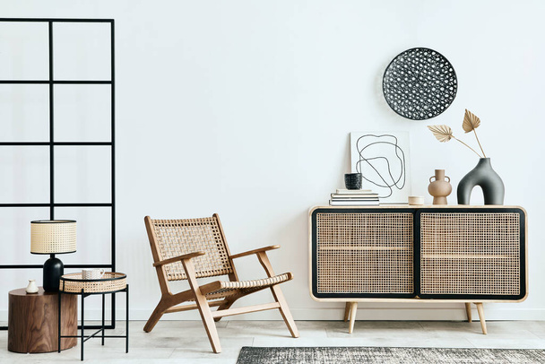 Stylish scandinavian living room interior of modern apartment with wooden commode, design armchair, carpet, leaf in vase, table lamp and personal accessories in unique home decor. Template. - 写真・画像
