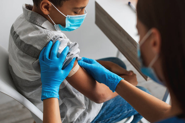 Афроамериканский мальчик получает вакцину против Covid-19 в помещении, обрезанный - Фото, изображение