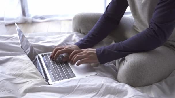 Vista cortada do freelancer usando laptop na cama  - Filmagem, Vídeo