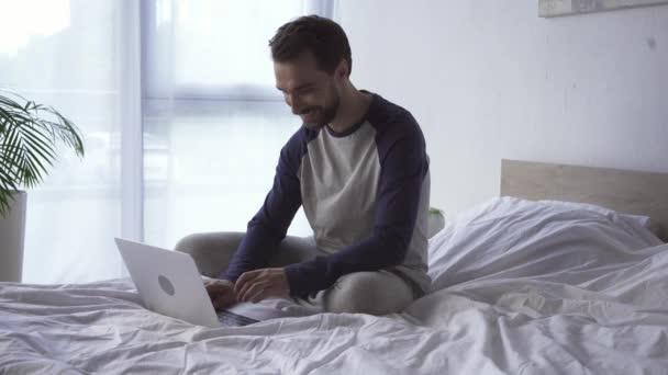 Веселый фрилансер с ноутбуком в спальне дома  - Кадры, видео