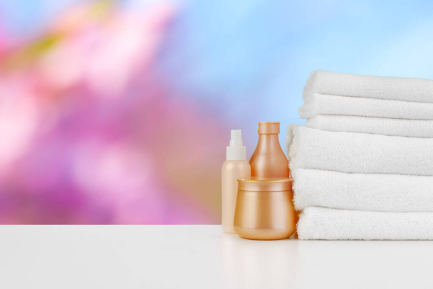 Spa still life with towels and skincare cosmetics against blurred background - Fotó, kép