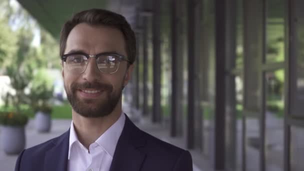 Homme d'affaires barbu à lunettes regardant la caméra à l'extérieur  - Séquence, vidéo