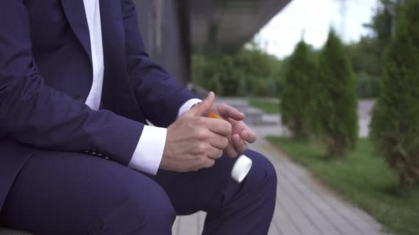 Rajatut näkymät liikemies kaatamalla pillereitä käsillä ulkona  - Materiaali, video