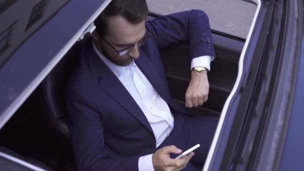 Vista aerea dell'uomo d'affari che utilizza lo smartphone in auto  - Filmati, video