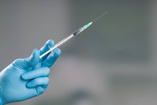 Gros plan de la main du médecin dans des gants médicaux avec une seringue de vaccin contre le coronavirus ou la grippe - Photo, image