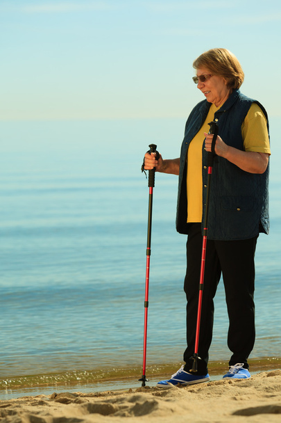 active woman senior nordic walking on a beach - Foto, Imagem