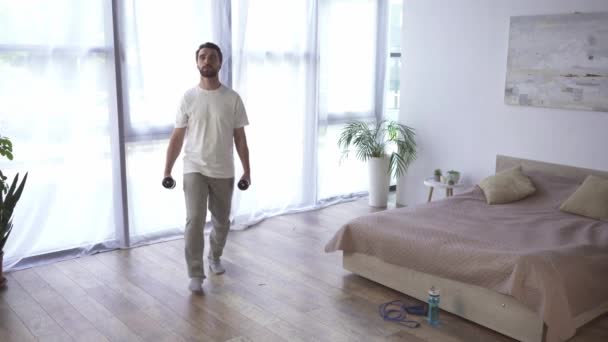 Hombre haciendo embestidas con mancuernas en el dormitorio  - Metraje, vídeo