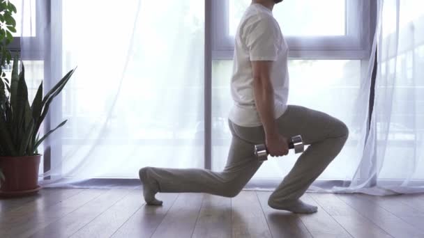 Gehakt uitzicht op de mens doet lunges met halters thuis  - Video