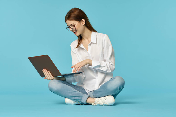 woman with laptop learning internet online education blue background - Foto, afbeelding