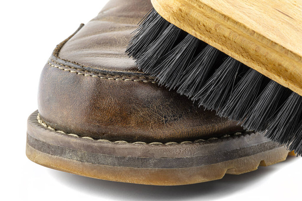 Macro photo of an old brown leather booties polished with paste, shoe brush lies on the shoe, isolated on a white background. - Photo, Image