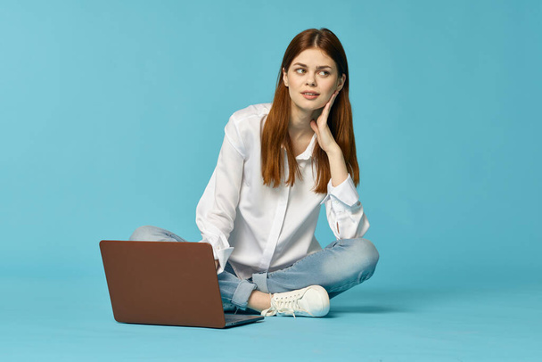 woman with laptop sitting on the floor learning student technology blue background - Valokuva, kuva