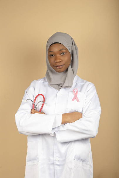 Gesundheitsversorgung für muslimische Frauen. Porträt einer afroamerikanischen Ärztin mit Kopftuch und weißem Mantel, die mit verschränkten Armen posiert. Vertikales Bild - Foto, Bild