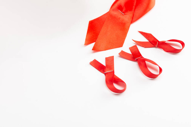 Health care and medicine concept. AIDS awareness. Red awareness ribbons of different sizes on a white background. International AIDS Day - 写真・画像