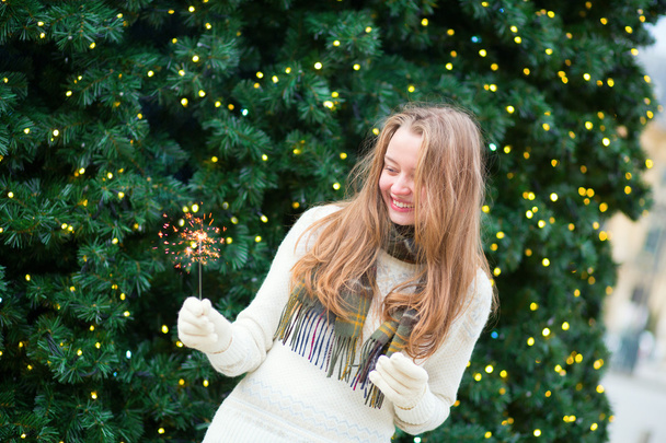 Girl with a sparkler near brightly Christmas tree - Fotografie, Obrázek