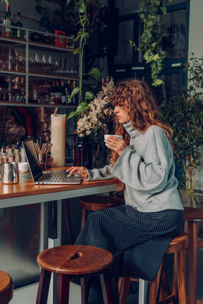Ділова жінка з кучерявим волоссям працює в кафе віддаленого офісу за допомогою ноутбука. Вибірковий фокус
. - Фото, зображення