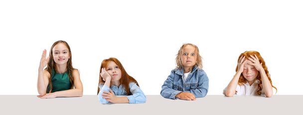Collage von vier Kindern, Mädchen, Schülern, die mit unterschiedlichen Gefühlen am Tisch sitzen, isoliert auf weißem Hintergrund - Foto, Bild